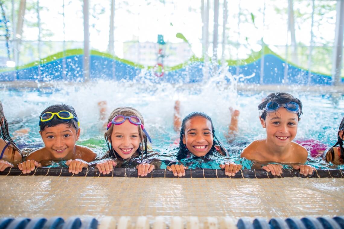 画像:スイミングプールで笑顔で泳ぐ子供達